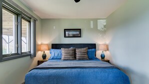 A bedroom with a large bed, two bedside tables with lamps, a framed picture on the wall, and a window with blinds. - Pets welcomed, fully fenced in yard. Beautiful 1BR suite w full kitchen, WI-FI  (Candler)