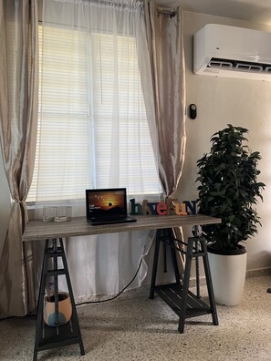 Work in comfort with a dedicated workspace featuring a desk, laptop, and potted plant.