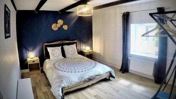 Une chambre à coucher avec un grand lit, un lustre, une table de chevet et une fenêtre avec des rideaux.