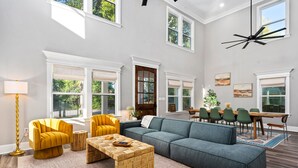 A spacious living room with a large sectional sofa, a coffee table, and a dining area with a table and chairs. - Outdoor Kitchen - Walk to Beach - Fire Pit - Dogs (Gulfport)