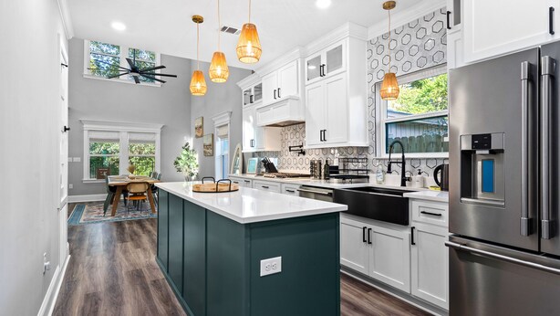 A modern kitchen with white cabinets, a central island, and stainless steel appliances. - Outdoor Kitchen - Walk to Beach - Fire Pit - Dogs (Gulfport)