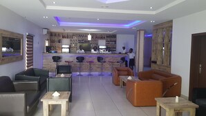 Eine moderne Bar mit Holztresen, Barhocker und einer Sitzecke mit Sofas und Tischen.