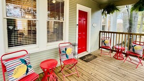 A porch with red metal chairs and a red door.
