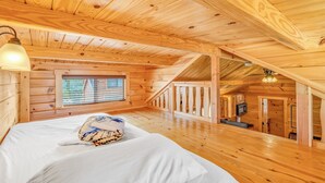 A wooden cabin interior with a bed, a window, and a staircase leading to an upper level. - Cabins at Bonefish Bay (Marathon)