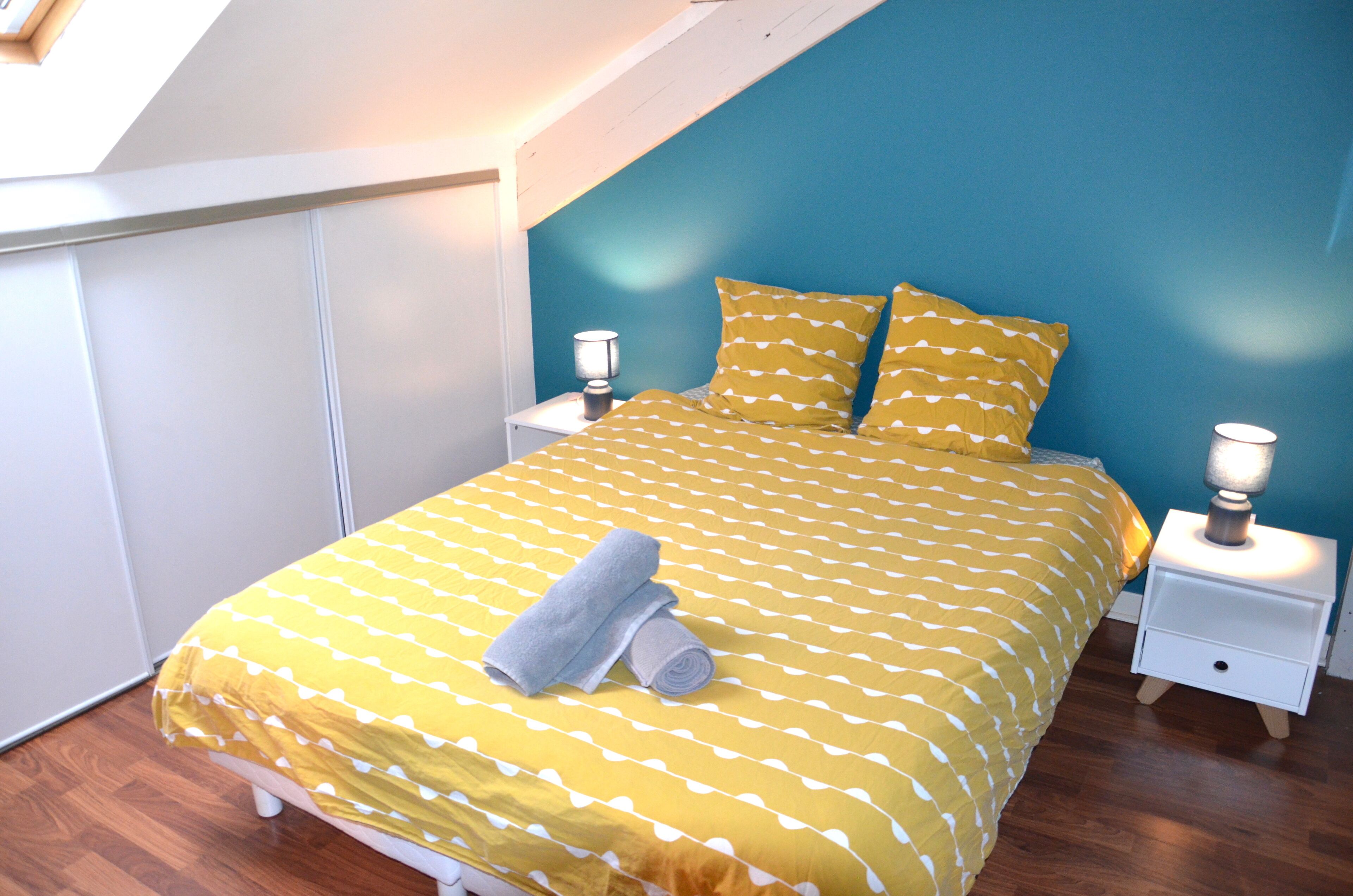 A bedroom with a bed, two bedside tables, and a lamp on each side.
