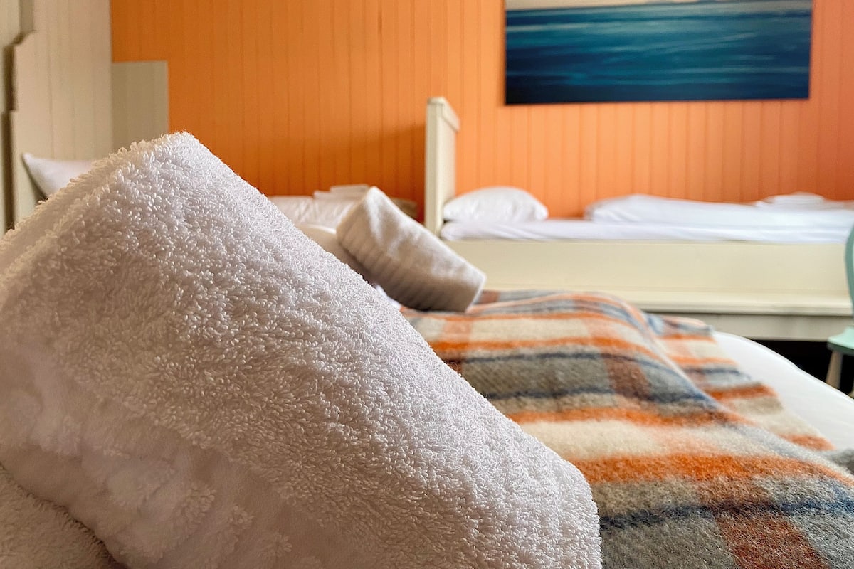 A hotel room with a bed, a white towel, and a painting of a blue ocean on the wall.