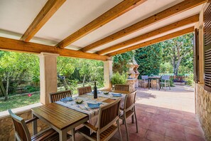 An outdoor patio with wooden tables and chairs, a pergola overhead, and a view of a garden. - Cuixac, A Quiet Country Villa IN Pollensa (Pollença)
