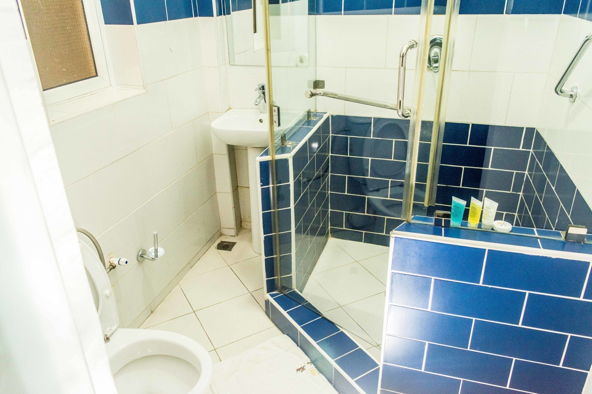 Een badkamer met een witte wastafel, een douchecel met glazen wanden en een toilet.