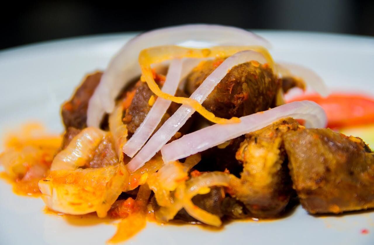 A plate of food with meat, onions, and a red sauce.
