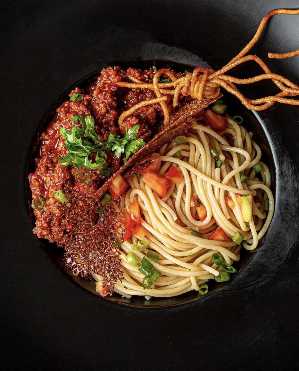 En skål med spaghetti, köttbullar och grönsaker.