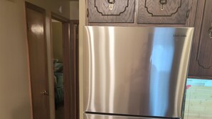 Un réfrigérateur en acier inoxydable dans une cuisine dotée de meubles en bois et d’un plancher en bois.