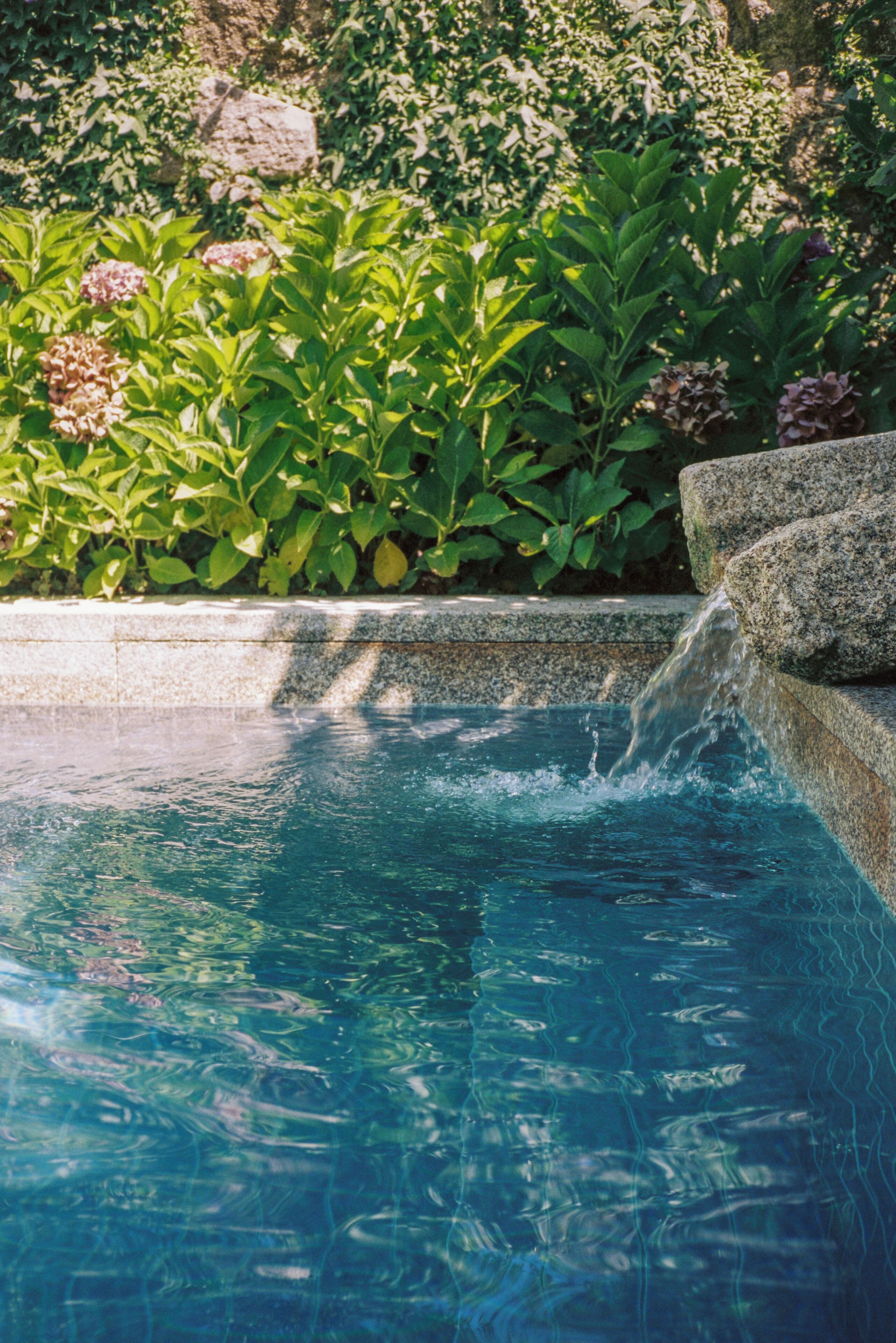 A clear pool with a stone edge and a waterfall feature.