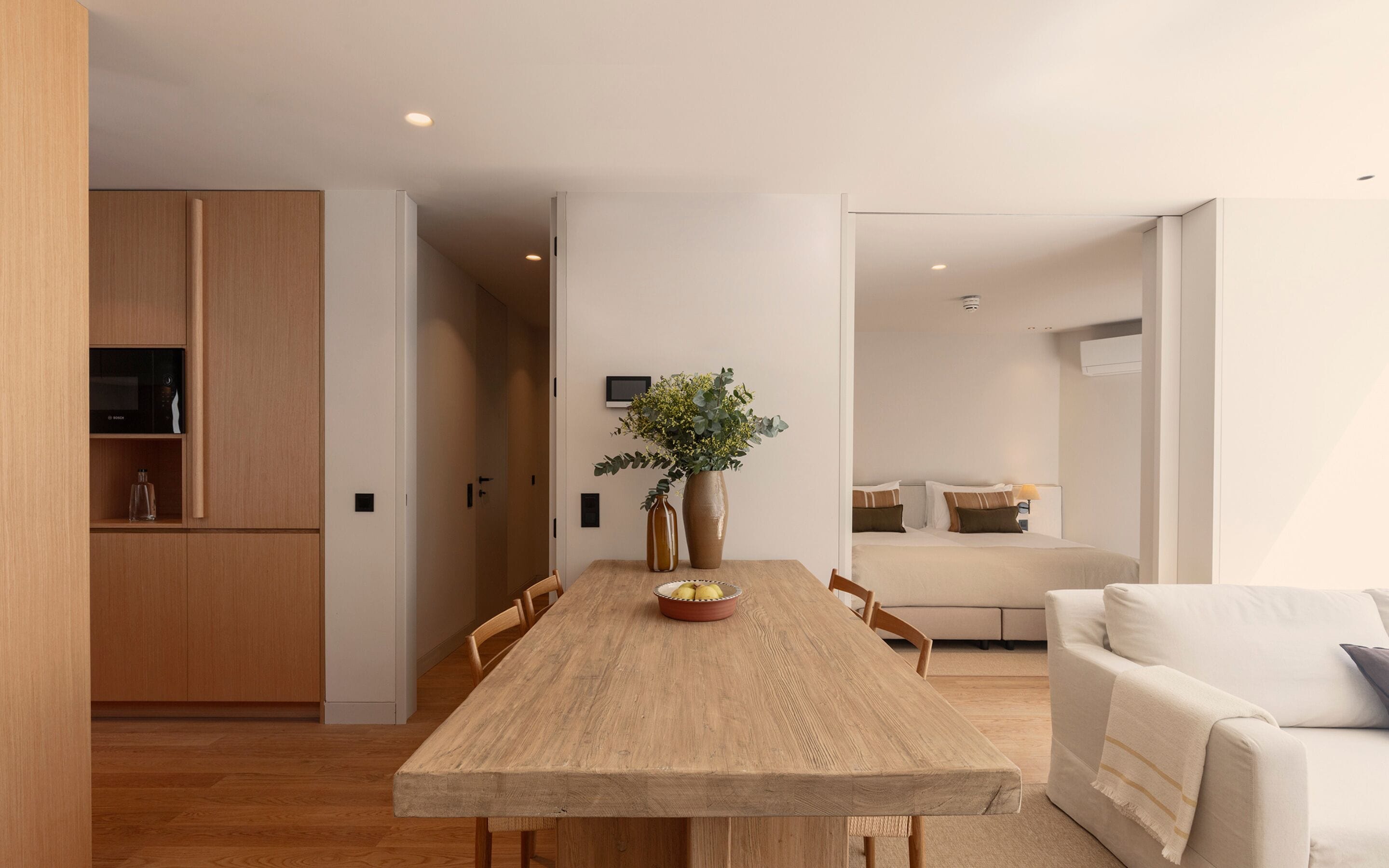 Une cuisine moderne avec des meubles en bois, une table à manger avec des chaises et un vase rempli de fleurs.