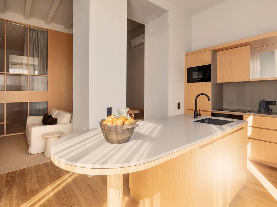 A modern kitchen with a central island, wooden cabinetry, and a built-in microwave.