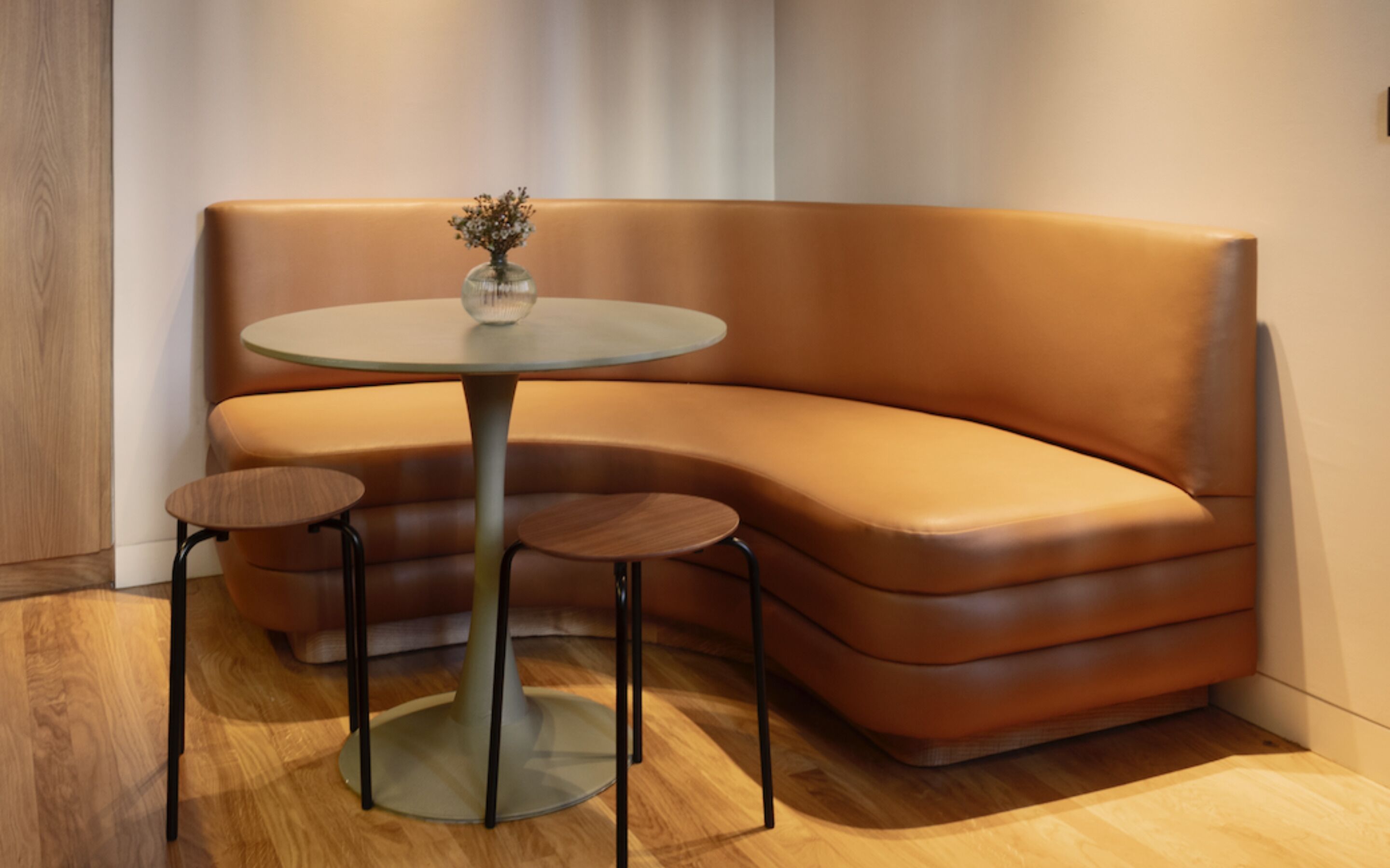 Een moderne kamer met een gebogen leren bank, een glazen tafel en twee bijpassende fauteuils.