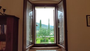 Una habitación con un ventanal que ofrece vistas a un paisaje verde con árboles y colinas.