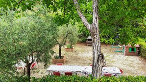 Un jardín con mesas de picnic, una casita de juegos de madera y un árbol.