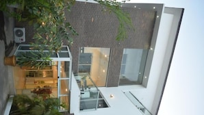 A modern building with a glass facade, a staircase, and a balcony with potted plants. - Wallgate Apartments Abuja (Abuja)
