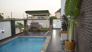 A rooftop swimming pool with lounge chairs and a covered seating area. - Wallgate Apartments Abuja (Abuja)