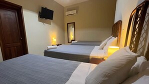 Habitación de hotel con dos camas, un televisor montado en la pared y un equipo de aire acondicionado.