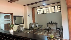 Una sala de estar con un sofá, una mesa de centro, un ventilador de techo, un reloj y una ventana con barrotes.
