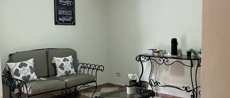 Una sala de estar con un sofá, una mesa de centro y una mesita con una planta.