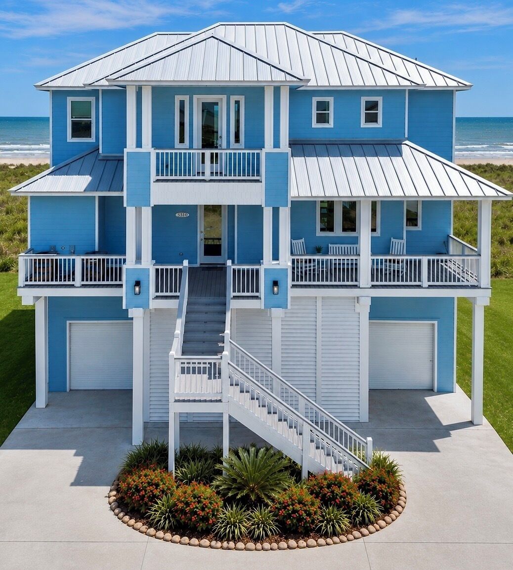 Une maison à deux étages située en bord de mer, dotée d’un balcon, d’un escalier et d’un garage.