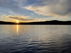 Een kalm meer bij zonsondergang, met de zon die in het water weerspiegelt.