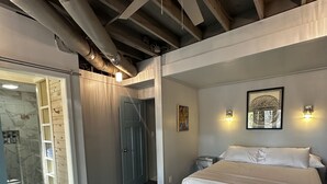 A bedroom with a large bed, a bench, a ceiling fan, and a door leading to a bathroom. - Lake Jocassee Home - Incredible Dock and Mountain and Sunset Views - Devils Fork (Salem)