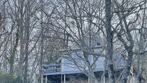 A large, two-story building with a stone facade and multiple balconies, surrounded by dense trees and underbrush. - Lake Jocassee Home - Incredible Dock and Mountain and Sunset Views - Devils Fork (Salem)