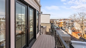 A modern building with large windows and a wooden deck. - The Adams | West Elm 5BR Townhouse in Bloomingdale (Washington)