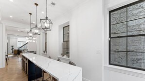 A modern kitchen with a marble countertop, pendant lights, and a large window. - The Adams | West Elm 5BR Townhouse in Bloomingdale (Washington)