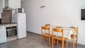 Uma cozinha compacta com micro-ondas, geladeira, forno e uma mesa de jantar com cadeiras.