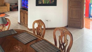 A dining area with a wooden table, chairs, and a television on a stand. - CALLE JARDIN FINCA HOTEL  (Armenia)