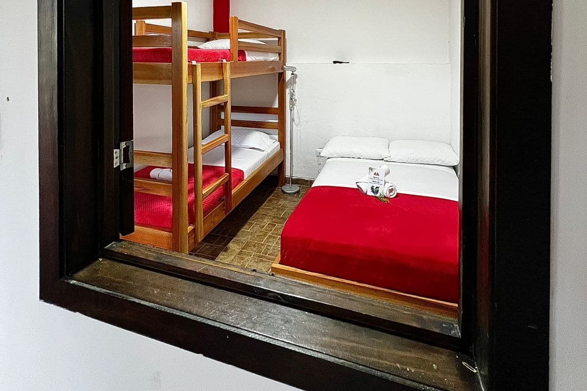 A room with bunk beds, a red bedspread, and a white wall.