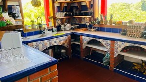 A kitchen with blue and white tiles, a brick oven, and various kitchen utensils and appliances. - CALLE JARDIN FINCA HOTEL  (Armenia)
