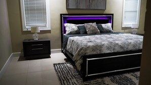 Ein Schlafzimmer mit einem Bett, Nachttischen, einem Teppich und einem Wandbild.