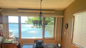A dining area with a table, chairs, a chandelier, and a view of the water.