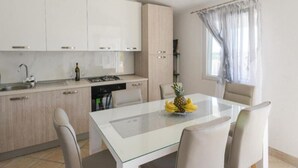 A modern kitchen with white cabinets, a dining table with chairs, and a window with sheer curtains. - Seclude charmy house with pool 200m from sea (Duboka)