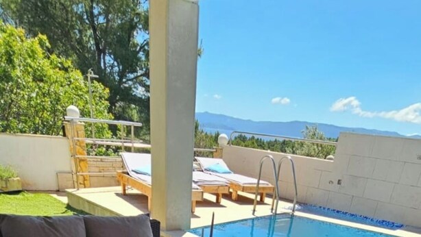 A poolside area with a sofa, lounge chairs, and a view of mountains. - Seclude charmy house with pool 200m from sea (Duboka)