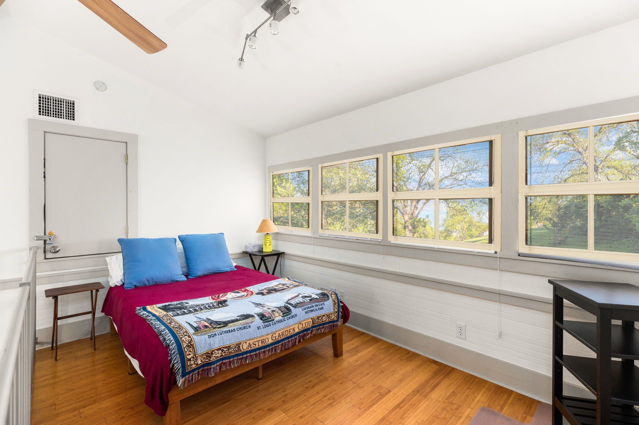 Un dormitorio con cama, ventana con vistas, mesita de noche y lámpara.