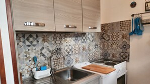 A kitchen with a patterned backsplash, stainless steel sink, and white appliances. - Seaside B&B - Bright and breezy apartment with large garden 100 m from the sea. (Anzio)
