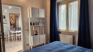A bedroom with a bed, a desk, and a window with curtains. - Seaside B&B - Bright and breezy apartment with large garden 100 m from the sea. (Anzio)