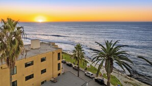 Un bâtiment situé sur la côte, offrant une vue sur l’océan au coucher du soleil.