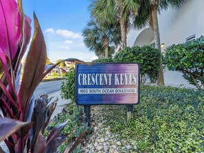 Straßenschild für Crescent Keyes, 1903 South Ocean Boulevard, umgeben von Grünflächen und Palmen.