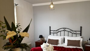 Ett välordnat sovrum med en säng, ett nattduksbord, en lampa och en vas med blommor.