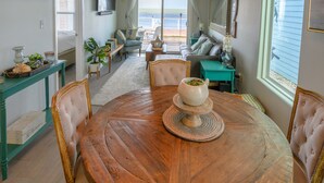 A dining area with a wooden table, chairs, and hanging pendant lights. - Bungalow on South Padre Bay (Port Isabel)