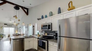 A modern kitchen with white cabinetry, stainless steel appliances, and decorative items on the upper cabinets. - Bungalow on South Padre Bay (Port Isabel)