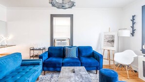 Ein modernes Wohnzimmer mit einem blauen Sofagarnitur, einem Couchtisch und einem Gemälde an der Wand.
