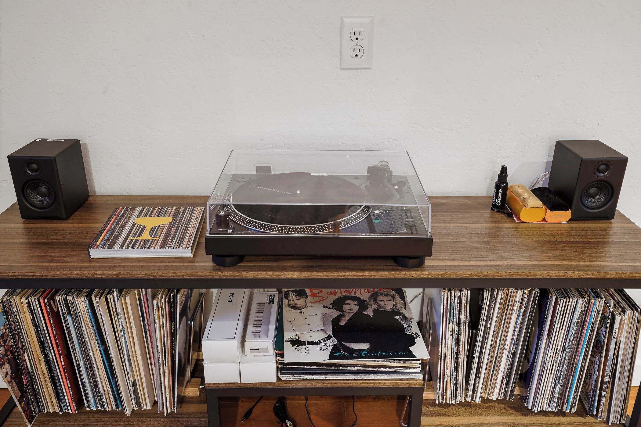 A wooden table with a turntable, speakers, and vinyl records.